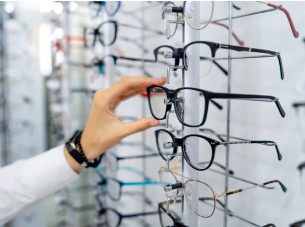 A hand reaching for a pair of glasses