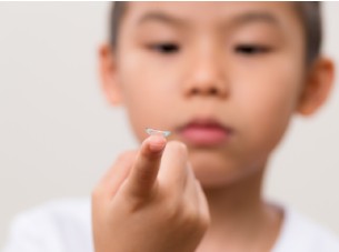 boy looking at her scleral lenses on her finger
