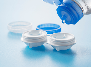 Contact lenses in a case with solution being poured from a bottle